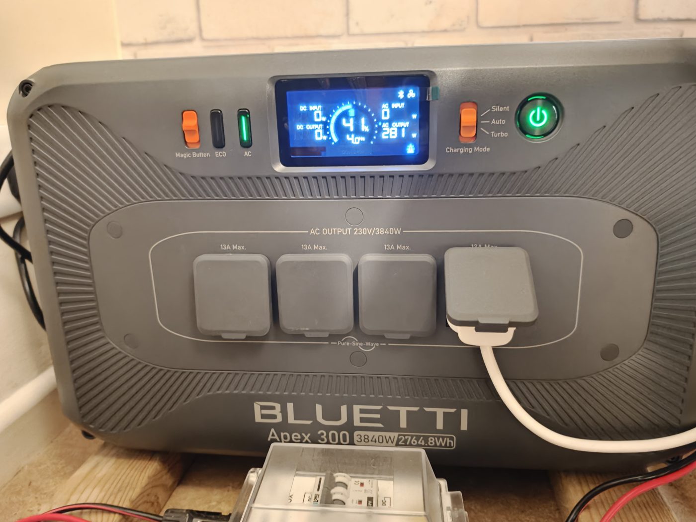The front of my Bluetti Apex 300: the lit display, charging mode switch, and four UK sockets under the label AC output 230V/3840W, with one plug in.