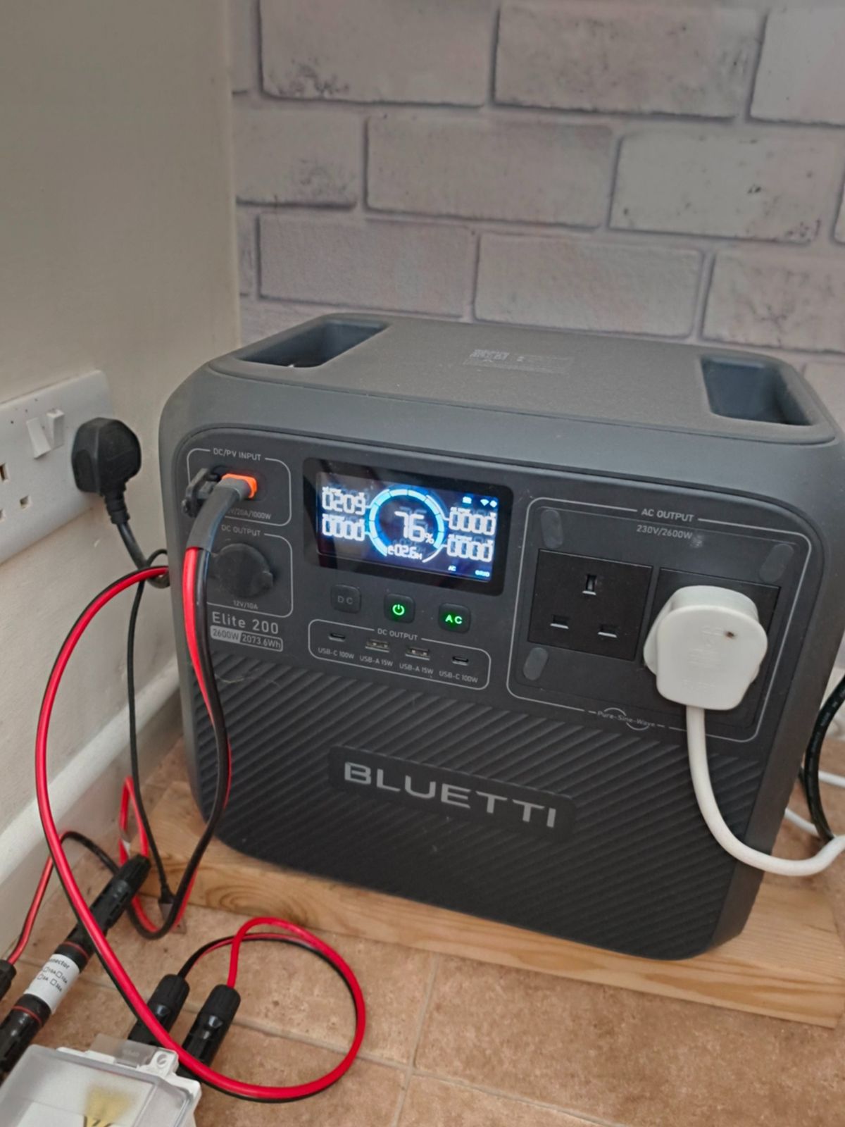 My Bluetti Elite 200 V2 on a wooden board at home, with solar cables plugged into the input and the homelab plugged into an AC socket. The screen shows 76% charge.