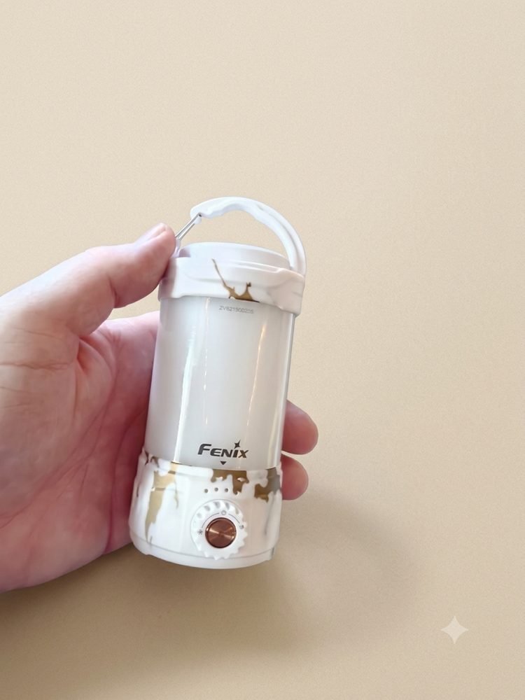 The white marble Fenix CL26R Pro lantern held in my hand, showing its size and the dial on the base.