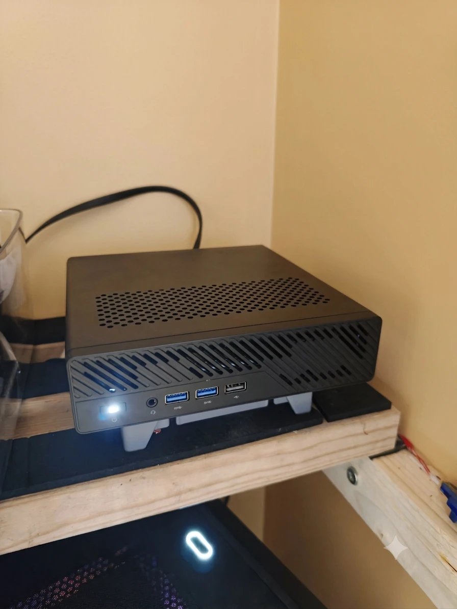 My Minisforum MS-A2 on a wooden shelf in my server room, power light on, sitting on a grey 3D-printed stand with a fan underneath.